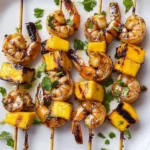 Grilled shrimp and mango skewers on a platter